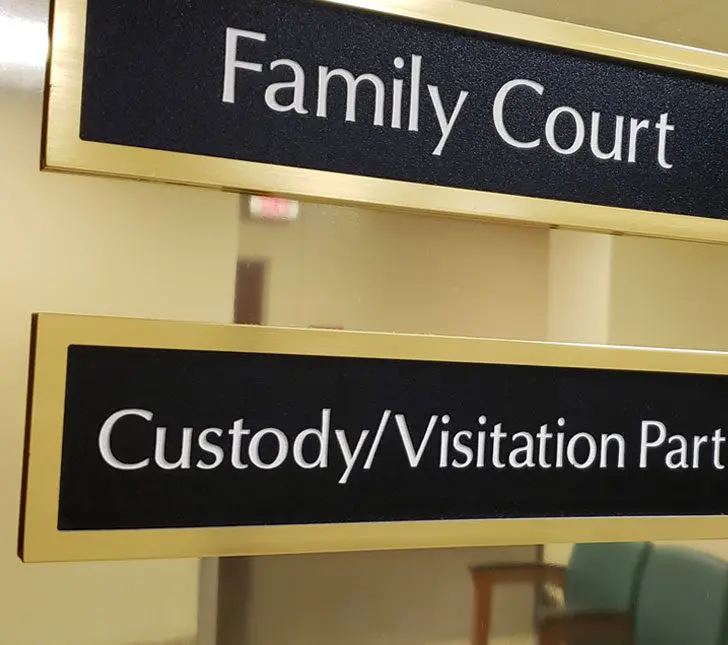 A sign in front of a building that says " family court custody / visitation policy ".